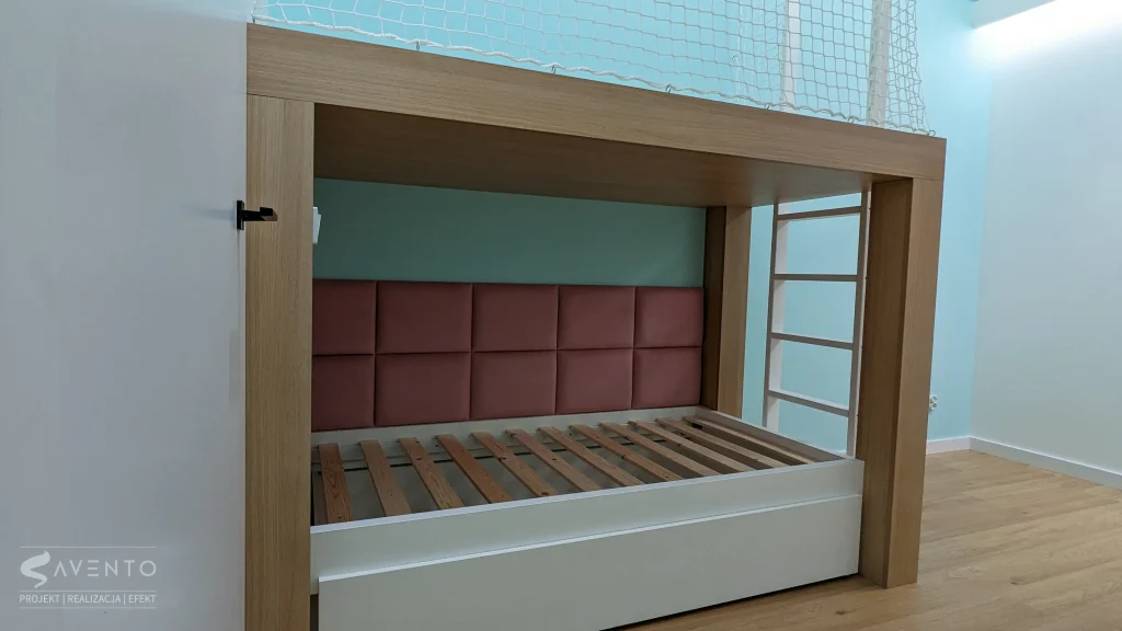 Łóżko z szufladą na kółkach gumowych. Na ścianie tapicerka w różowe prostokąty. Projekt i wykonanie Savento
