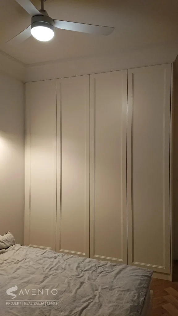 Szafa w sypialni z frezowana ramka na frontach w lakierze półmat. Oświetlenie włączane po otwarciu frontów. Projekt TONWTON, wykonanie Savento
