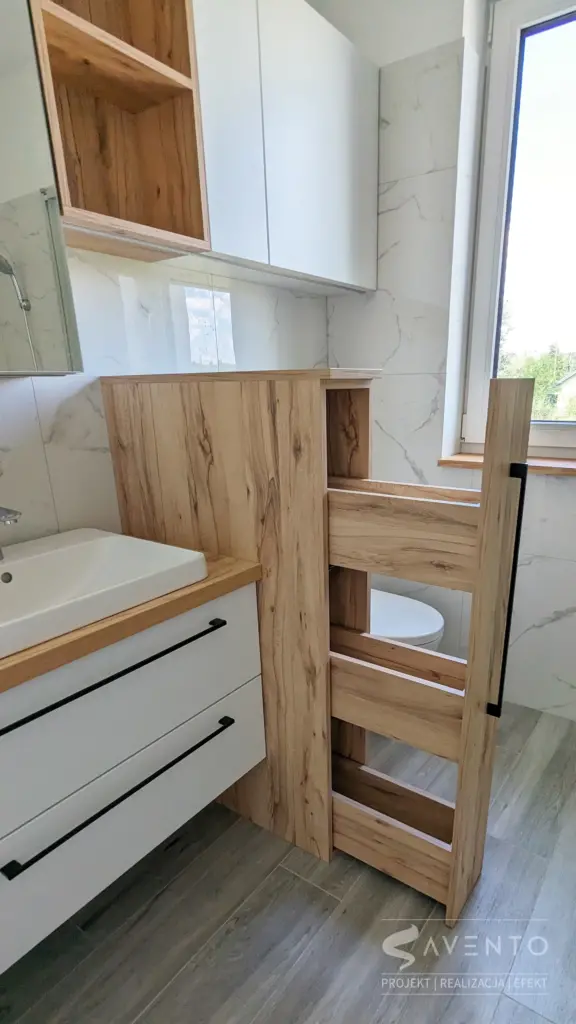 Zabudowa łazienki z szafka w lustrze nad umywalką. Szafka z szufladami jako oddzielenie umywalki i geberitu. Projekt Savento